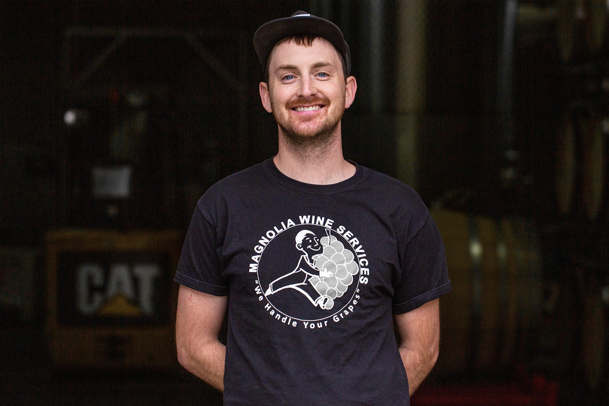Winery Assistant Seph Scheid smiling while working in the cellar at the Bedrock winery